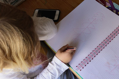 High angle view of girl drawing on book