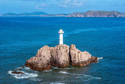 Lighthouse by sea against sky