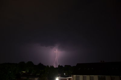 Lightning over illuminated cityscape against sky at night