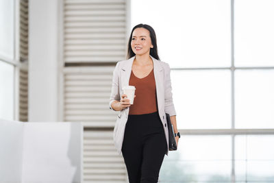 Full length of a young woman drinking coffee