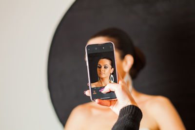 Cropped hand photographing woman against black background