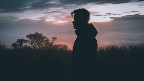 Silhouette woman standing by tree against sky during sunset