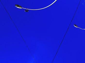 Low angle view of power lines against blue sky