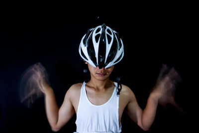 Portrait of woman standing against black background