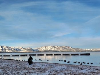 Scenic view of lake by snowcapped mountain against sky