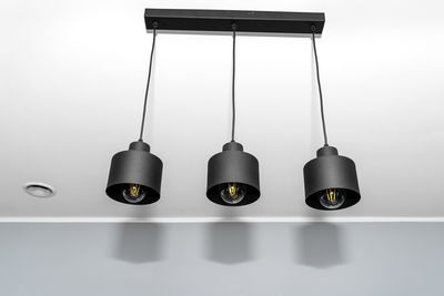 Modern chandeliers with tube shaped led bulbs, covered with matt black paint, three bulbs visible.