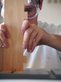 Close-up of carpenter working with wooden plank at desk