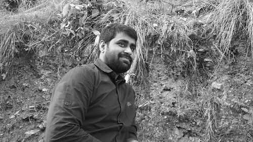 Young man looking away while standing by mountain