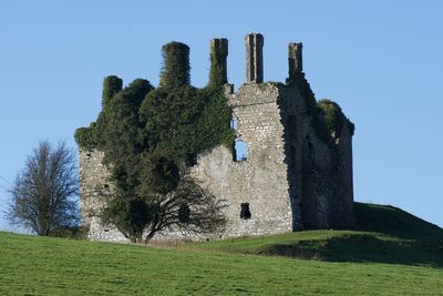 Low angle view of old ruins on field against clear sky