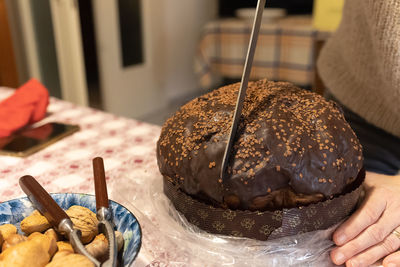 Cutting a slice of a typical italian christmas cake - panettone with chocolate.