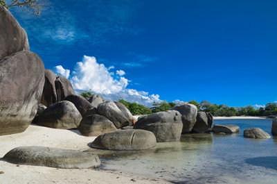 Rocks on beach against blue sky