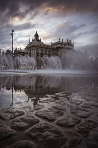 Fountain in front of building against sky