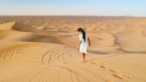 Rear view of woman standing at sandy beach