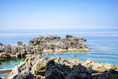 Scenic view of rocks in sea against sky