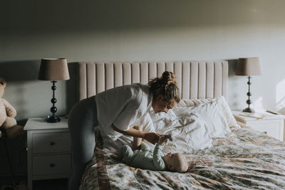 Mother playing with baby in bedroom