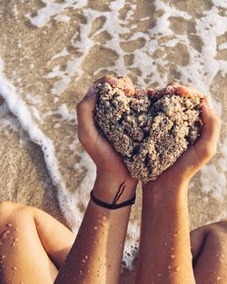 Low section of woman in heart shape on sand