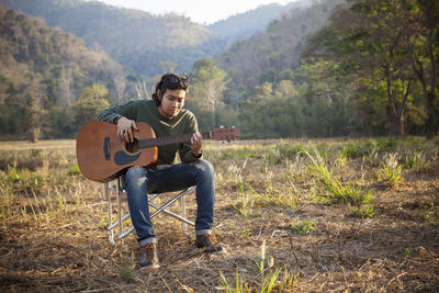 Asian man playing acoustic guitar on location