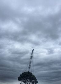 Low angle view of crane against cloudy sky