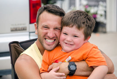 Uncle hugging young boy as they cuddle outdoors