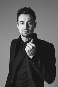 Portrait of young man standing against gray background