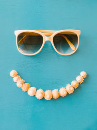 Directly above shot of sunglasses and seashells on blue table