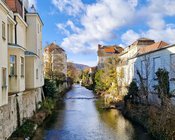 Buildings by river against sky