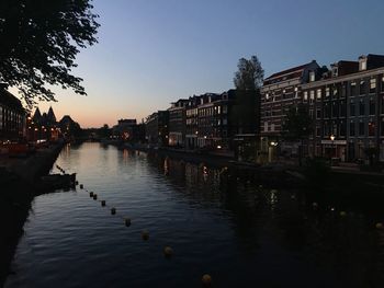 Canal amidst buildings against sky at sunset