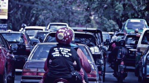 Rear view of people driving vehicle on road