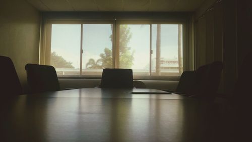 Empty chairs and table against window in board room