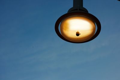 Low angle view of illuminated lamp against blue sky