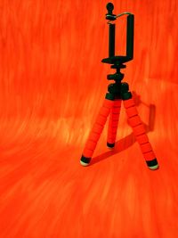 Close-up of tripod against orange wall