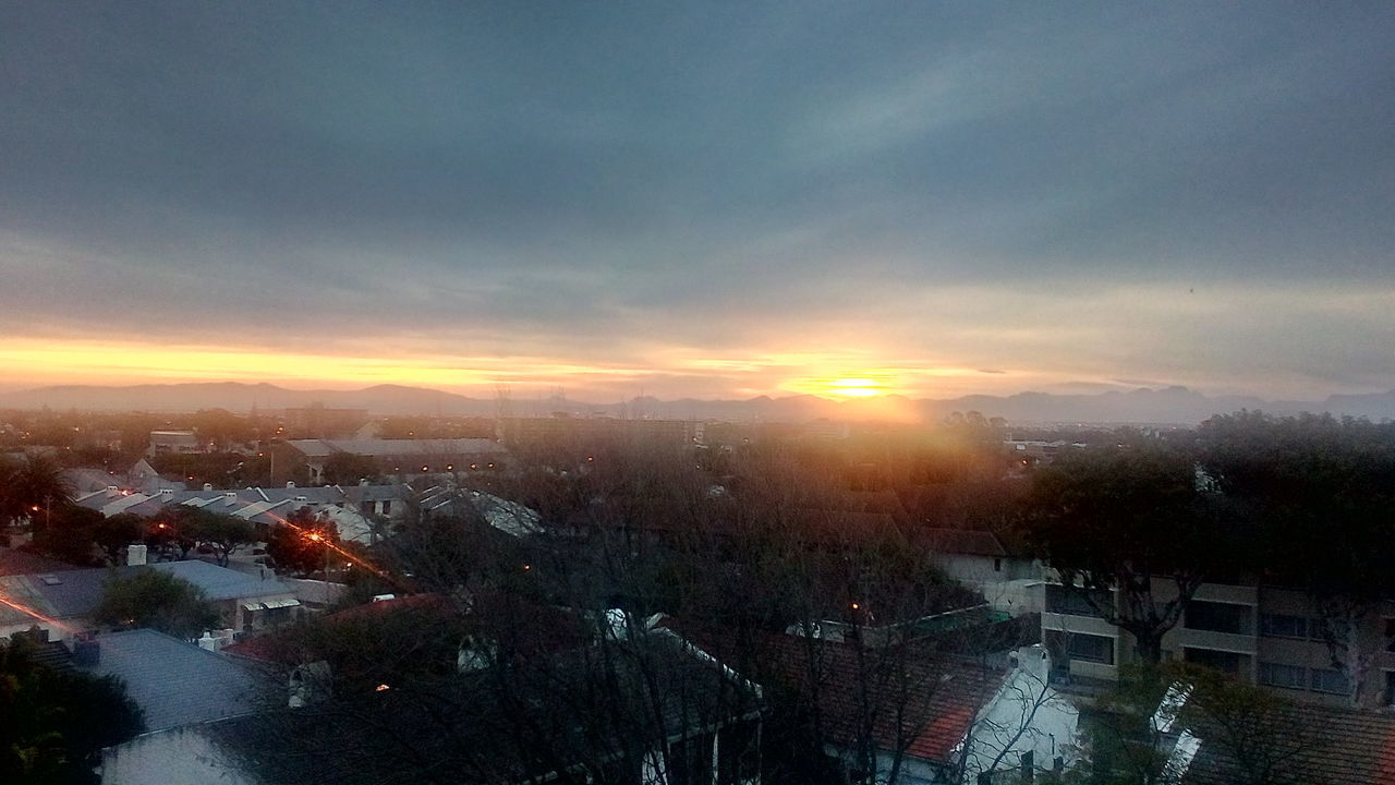 HIGH ANGLE VIEW OF BUILDINGS AND TREES AGAINST SKY AT SUNSET