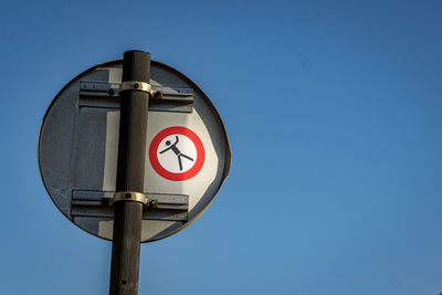 Low angle view of road sign against blue sky