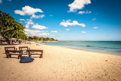 Benches at beach against sky