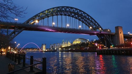 Illuminated bridge over river at night