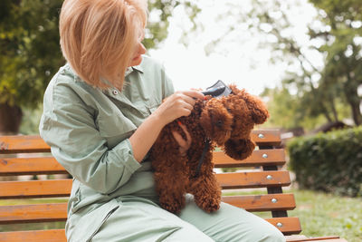 Rear view of woman with dog sitting on bench