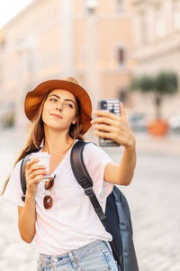 Young woman drinking water while standing in city