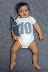 Child ten months lying on the bed with a soft toy hare in the hands