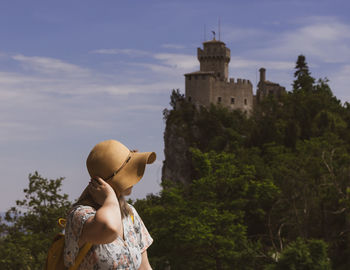 Rear view of young woman standing against sky