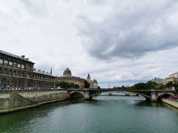 Bridge over river against cloudy sky