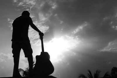Silhouette man standing against sky with guitar