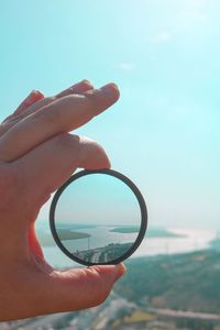 Close-up of hand holding sunglasses against sky