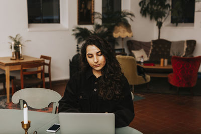 Young woman using phone while sitting on table