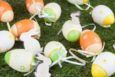 Close-up of wooden toys amidst multi colored eggs on grass field