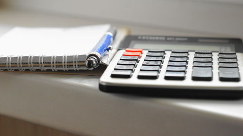 Close-up of calculator and spiral notebooks on table