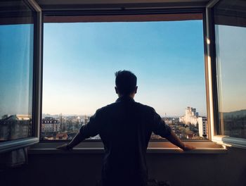 Rear view of man looking through window