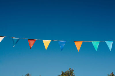 Low angle view of flags against clear blue sky