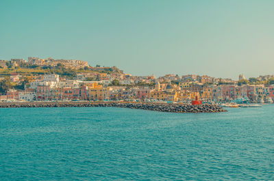 Aerial view of townscape by sea against clear sky