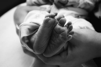 Cropped hands of parent holding newborn