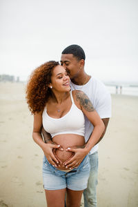 Mixed race couple embrac & pose on beach